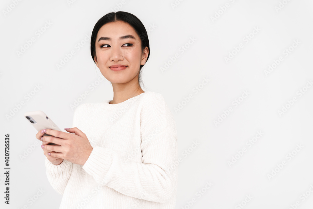 Asian pleased nice girl smiling while using mobile phone