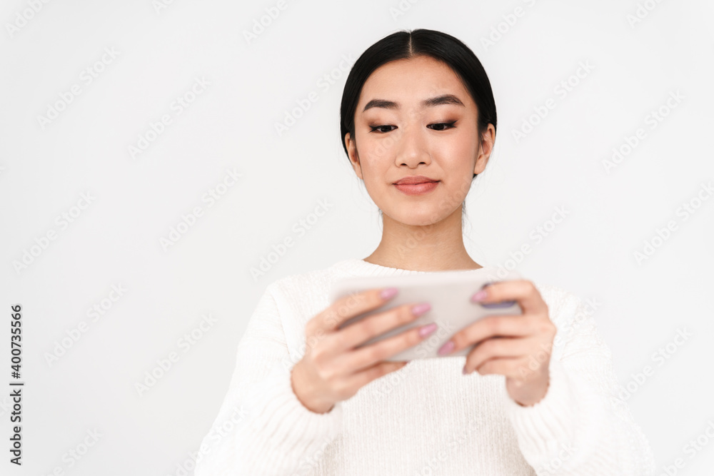 Asian pleased nice girl playing online game on mobile phone Asian pleased nice girl playing online game on mobile phone