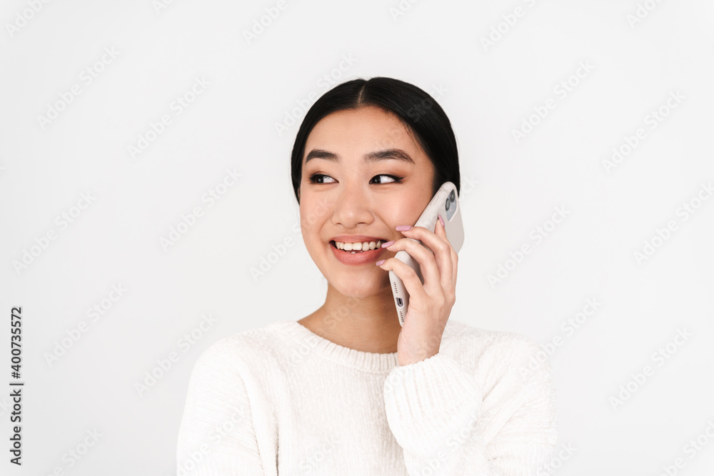 Asian pleased nice girl smiling while talking on mobile phone Asian pleased nice girl smiling while talking on mobile phone