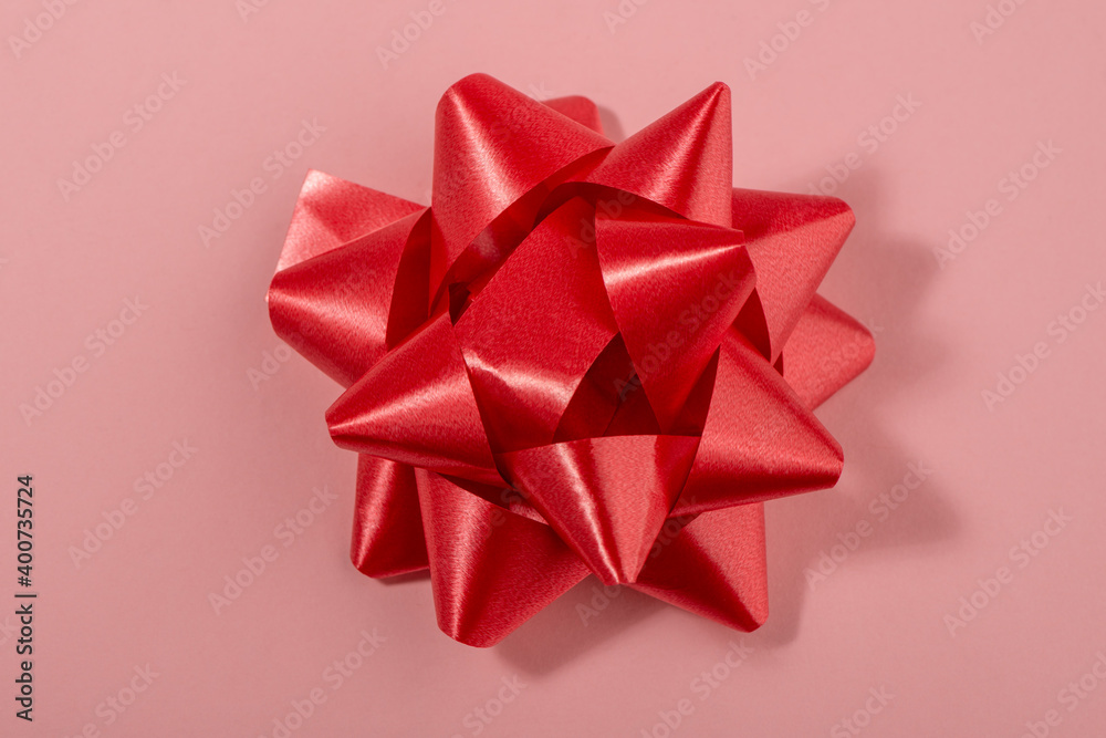 Red bow decoration on pink background, top view Red bow decoration on pink background, top view