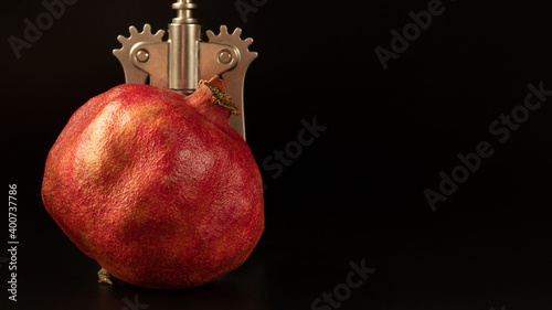 Foto Red pomegranate close-up with part of corkscrew on the backside of picture with black background and copy space in the right side