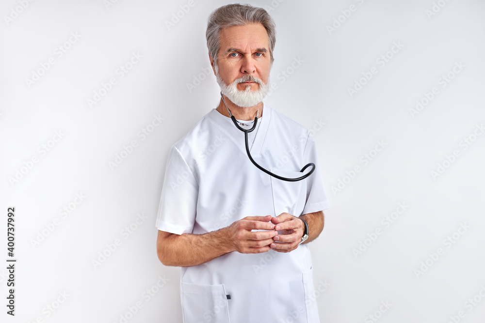 portrait of intelligent mature doctor man with gray hair in medical uniform with stethoscope, posing at camera, ready to help