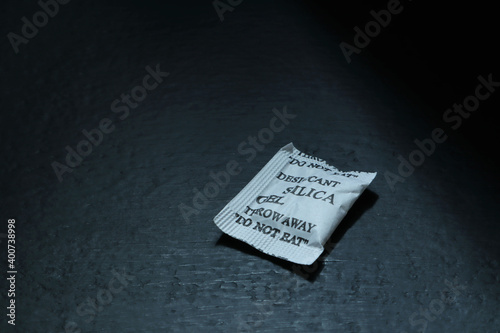 a pack of desiccant silica gel for preventing the humidity is put on the black wooden table photo