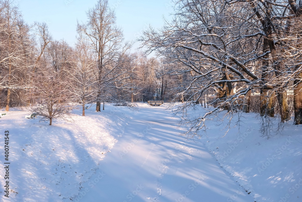 Snowy winter park with frozen river and bridge on sunny frosty day Snowy winter park with frozen river and bridge on sunny frosty day