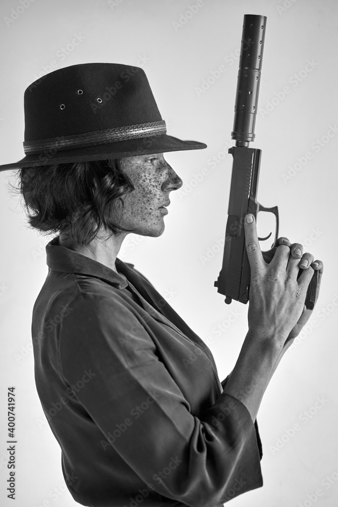 female with weapon against white background, isolated. detective redhead woman in black hat looking away, applying the weapon's barrel up female with weapon against white background, isolated. detective redhead woman in black hat looking away, applying the weapon's barrel up