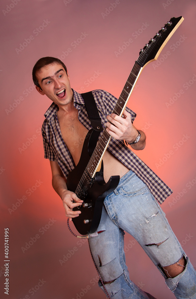 Young guitarist play music on his electric guitar with bright emotions. 