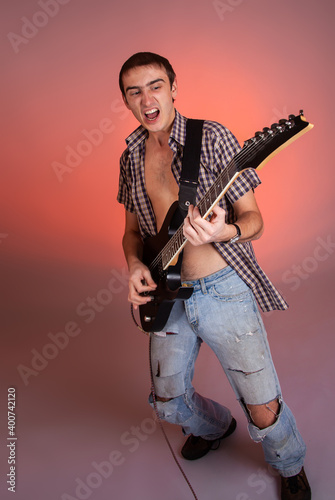 Young guitarist play music on his electric guitar with bright emotions. 