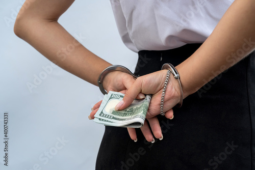 Close-up of woman hands in handcuffs holding dollar