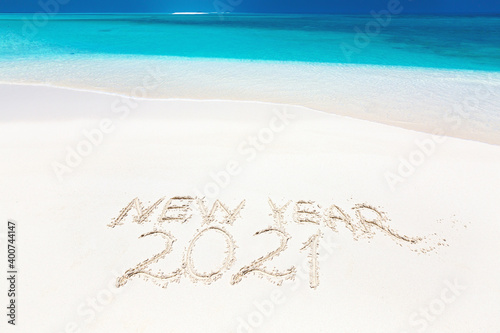 Handwritting inscription word NEW YEAR and number 2021 on perfect tropical sandy beach