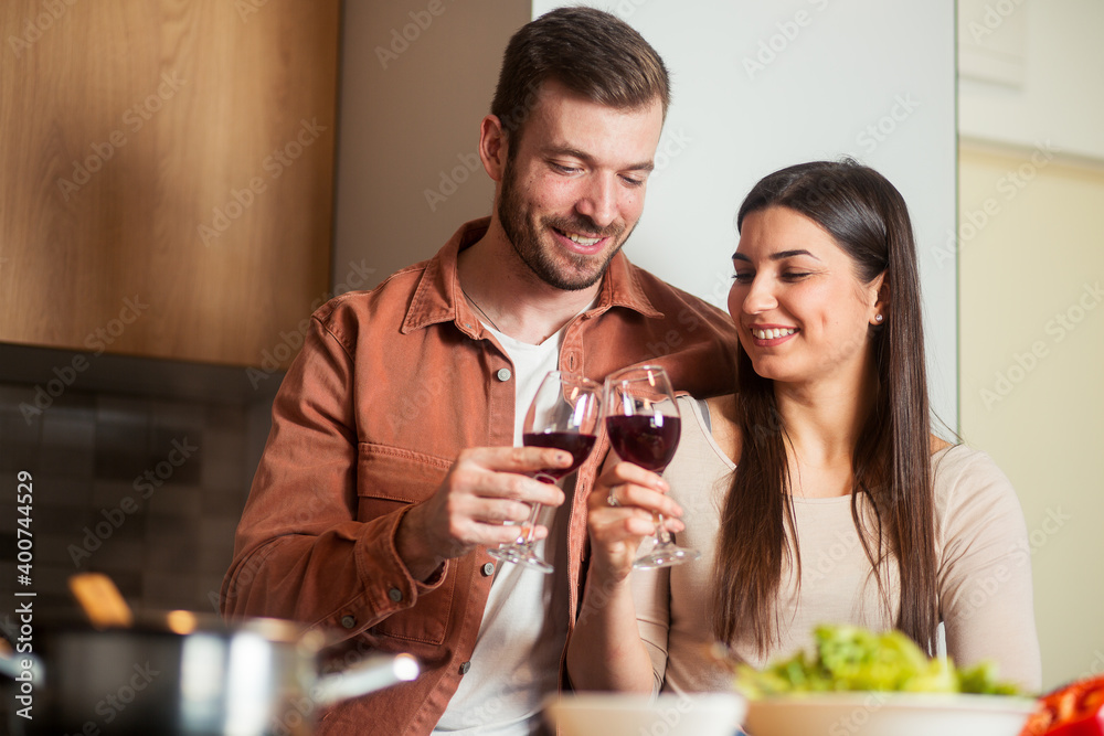 Young man and woman tasting wine while cooking together