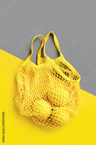 Yellow Cotton net bag with lemons on Grey background. Colors of the year 2021 Ultimate Grey and Illuminating. Color trend palette. Stylish background