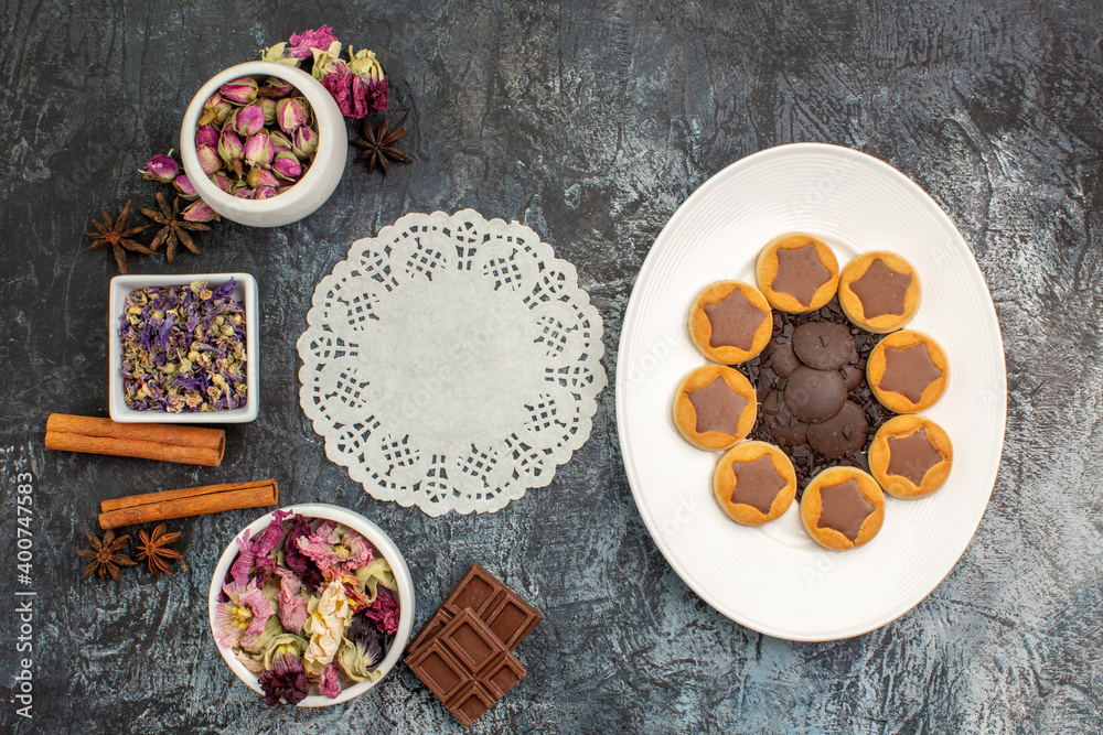 top view of dry flowers and assorted cookies on white plate and a piece of lace on grey ground top view of dry flowers and assorted cookies on white plate and a piece of lace on grey ground