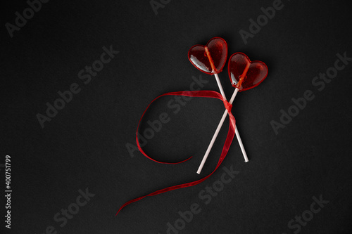 Heart-shaped sweets on a stick. Valentine's Day. Background. Candy on black background