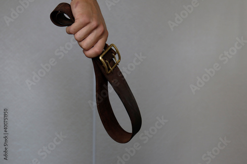 a belt in the hand of a father who wants to hit his child. domestic violence with copy space