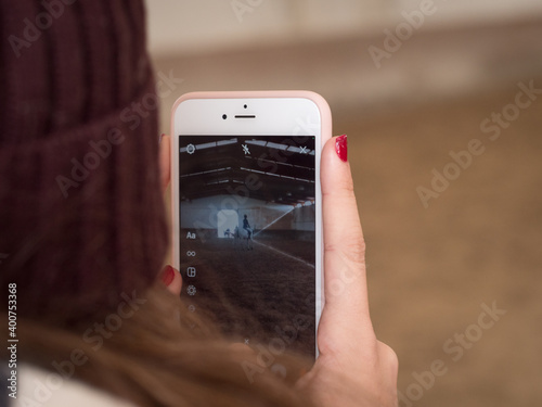 Female making video with phone at dressage contest.