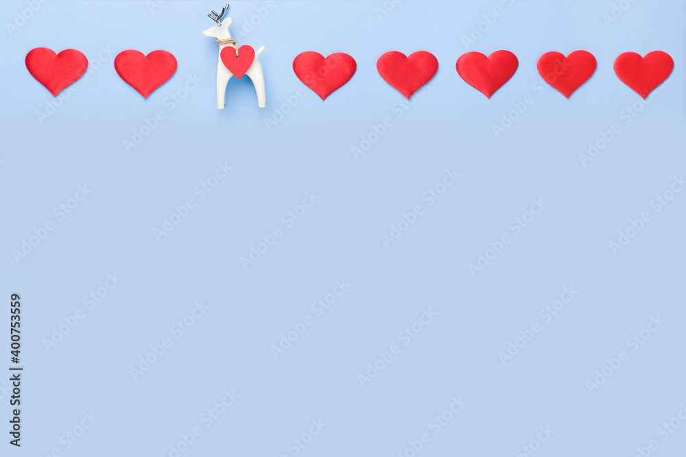 A row of hearts on a blue background with a small figure of a white deer. Valentine's Day Concept . Copy space. 
