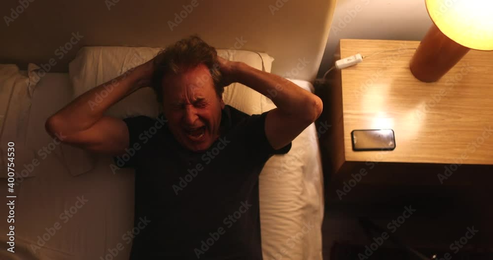 Tired old man rubbing eyes in fatigue, lying in bed, top view Tired old man rubbing eyes in fatigue, lying in bed, top view