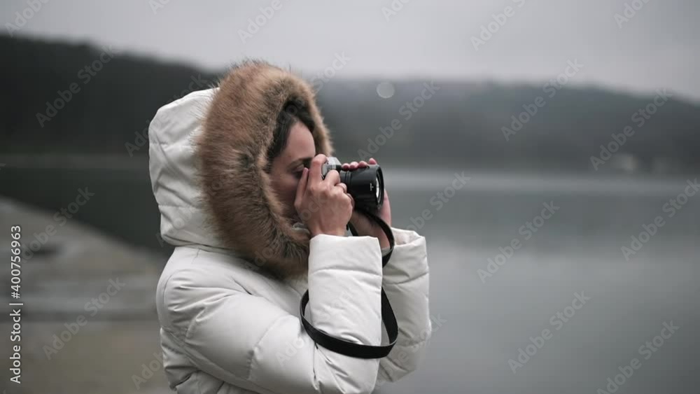 Woman in white winter coat taking photos and shooting video on a vintage camera Woman in white winter coat taking photos and shooting video on a vintage camera