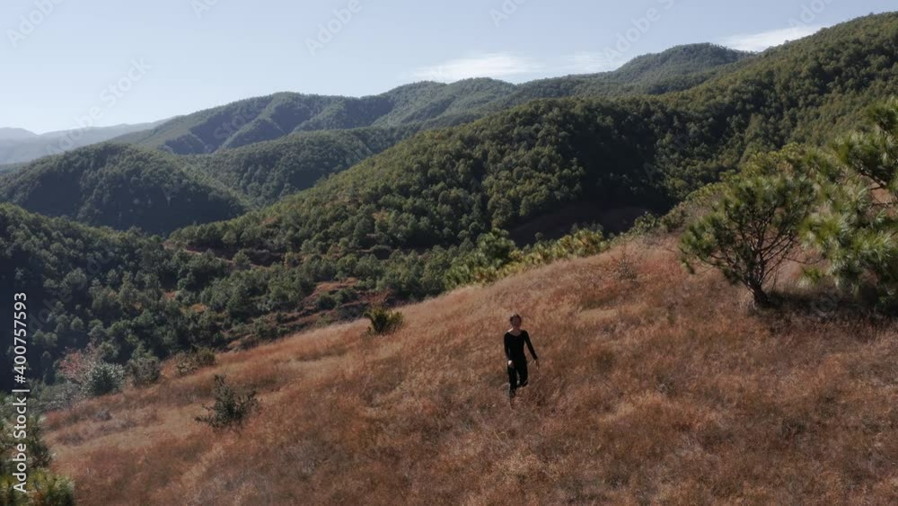 Female adventurer hiking across Chinese mountainside in Yunnan province, aerial Female adventurer hiking across Chinese mountainside in Yunnan province, aerial