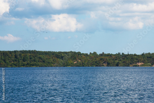 Blue lake blue sky and forest on the shore on a sunny summer day