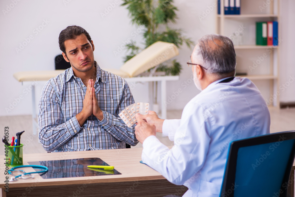 Obraz premium Young male patient visiting aged male doctor