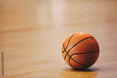 Orange basketball ball on wooden parquet. Close-up image of basketball ball over floor in the gym