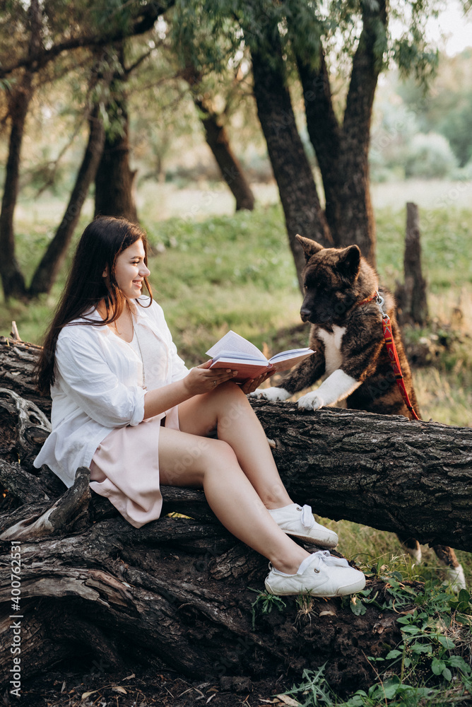 Obraz premium young girl in white clothes sits on a tree in the forest