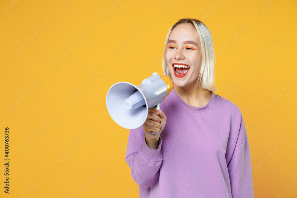 Smiling fun young blonde caucasian woman with bob haircut in casual basic purple shirt scream in megaphone announces discounts sale hurry up look aside isolated on yellow background studio portrait. Smiling fun young blonde caucasian woman with bob haircut in casual basic purple shirt scream in megaphone announces discounts sale hurry up look aside isolated on yellow background studio portrait.