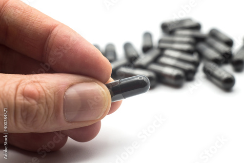 Closeup of black capsules of coal in hand on white background
