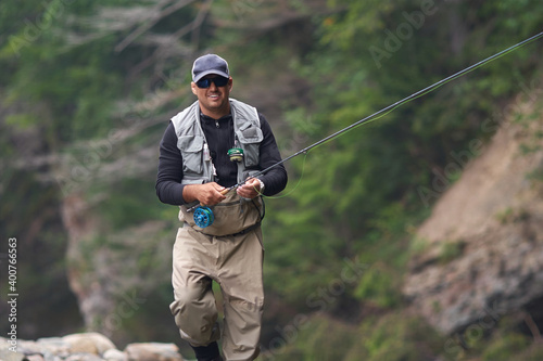 Smiling fisherman holding rod while standing in river
