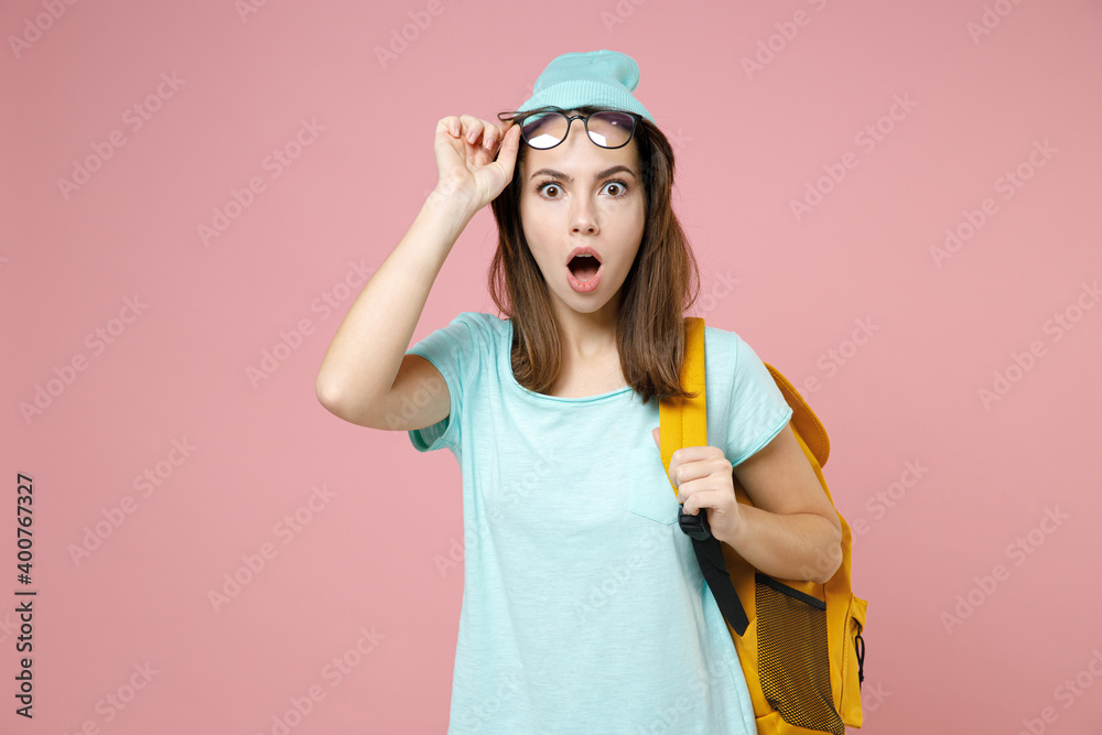Shocked worried young woman student in basic blue t-shirt hat eyeglasses backpack keeping mouth open isolated on pink background studio portrait. Education in high school university college concept. Shocked worried young woman student in basic blue t-shirt hat eyeglasses backpack keeping mouth open isolated on pink background studio portrait. Education in high school university college concept.