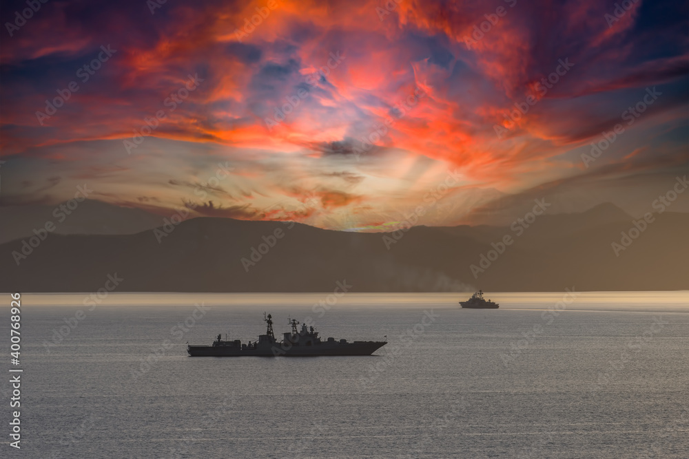 Seascape with silhouettes of warships at sunset