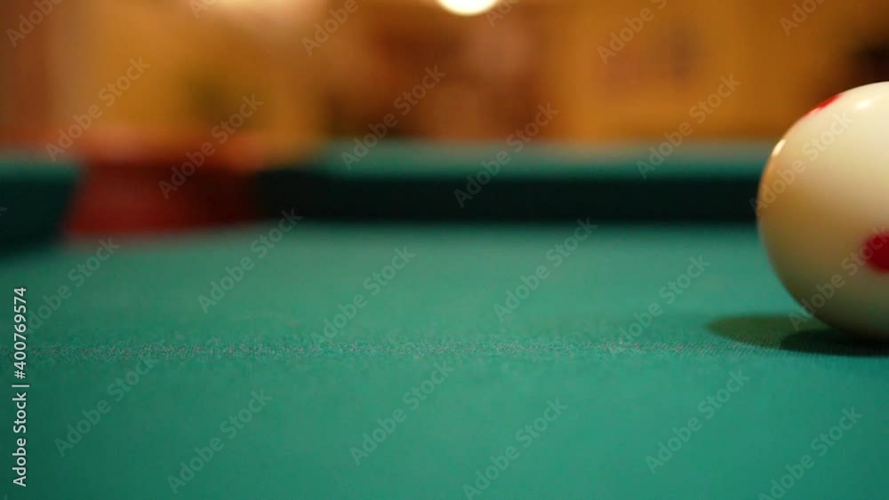 Slow Motion Billiards solid black 8 ball shot in corner pocket on pool table with green felt and brown pockets with the cue ball sliding out of frame Low Angle Close Up with Red Spinning Dots