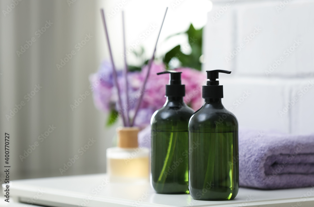 Soap dispensers and clean towel on white table. Space for text Soap dispensers and clean towel on white table. Space for text