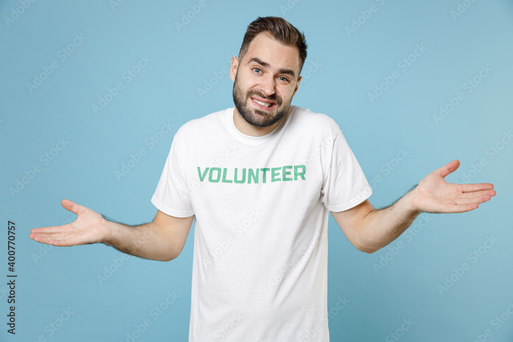 Confused puzzled young bearded man in white volunteer t-shirt spreading hands looking camera isolated on blue background studio portrait. Voluntary free work assistance help charity grace concept. Confused puzzled young bearded man in white volunteer t-shirt spreading hands looking camera isolated on blue background studio portrait. Voluntary free work assistance help charity grace concept.