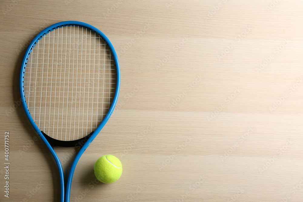 Tennis racket and ball on wooden table, flat lay. Space for text