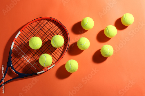 Tennis racket and balls on orange background, flat lay. Sports equipment © New Africa