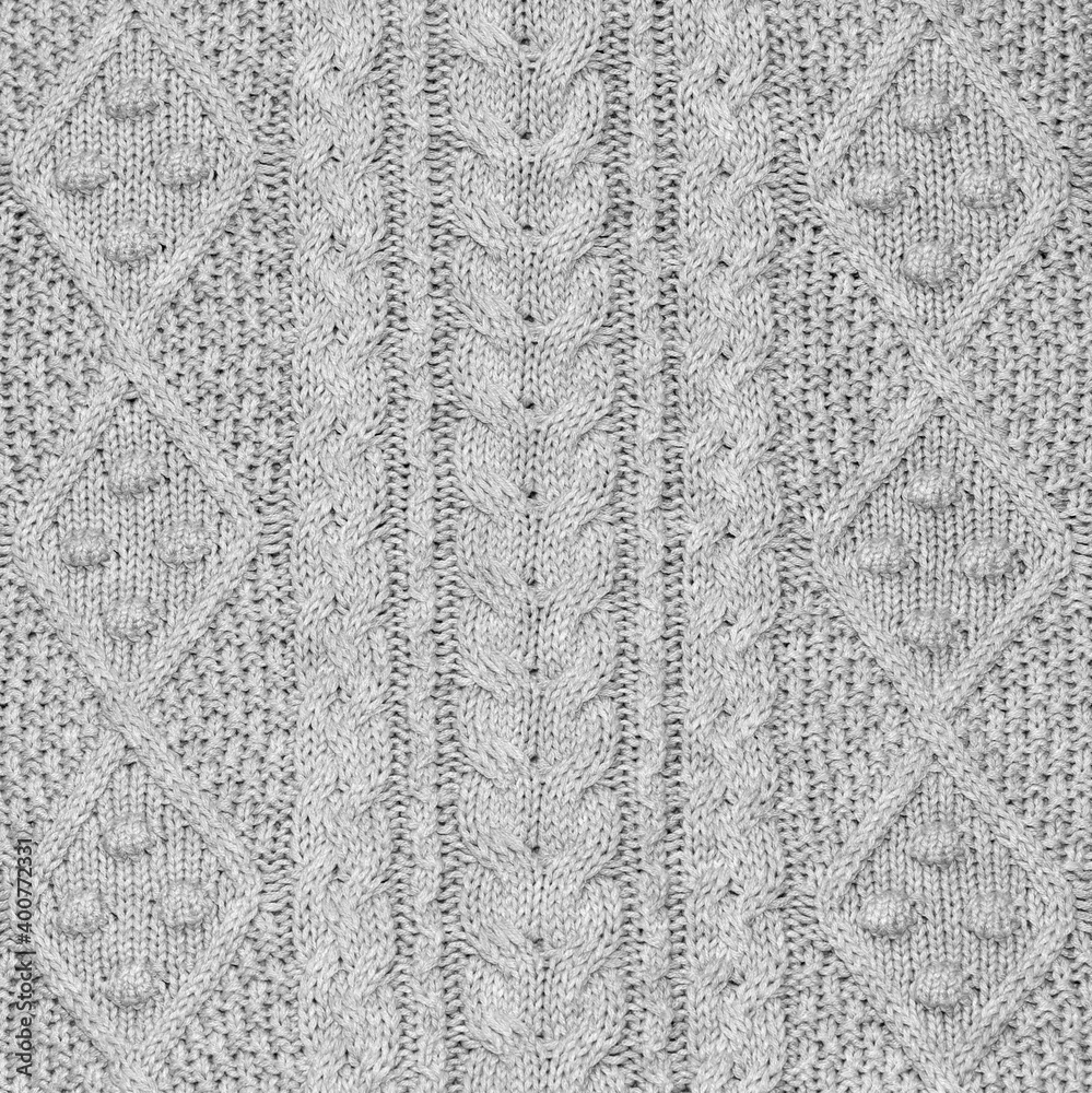 Silver grey knit fabric background or texture with vertical aran pattern of cables and rombs, square