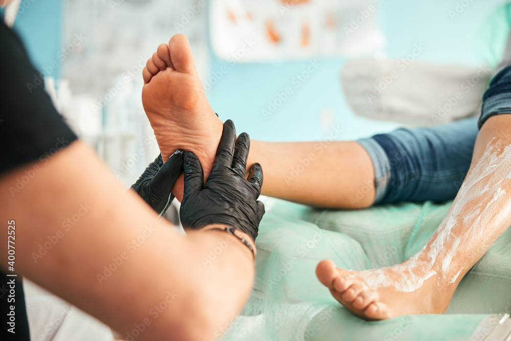 Focused photo on massagist doing foot treating procedure