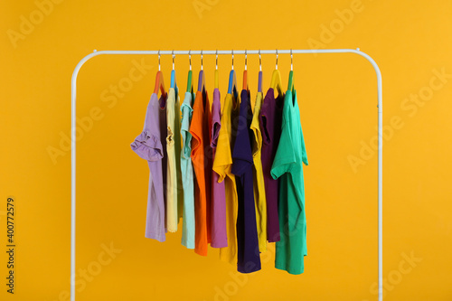 Rack with stylish children clothes on yellow background © New Africa