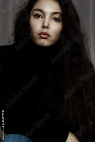 Portrait of beautiful brunette young woman in black looking at camera.