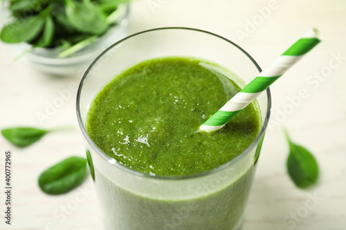 Delicious fresh green juice with straw in glass, closeup
