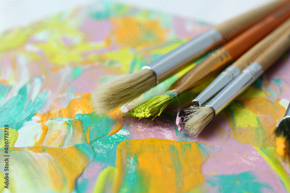 Fototapeta premium Set of different brushes on abstract colorful paint, closeup