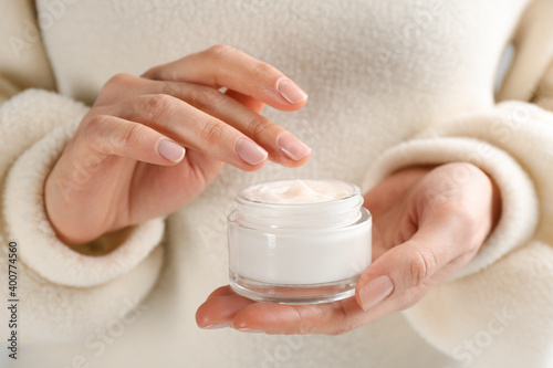 Woman holding jar of moisturizing cream, closeup. Cosmetic product for winter