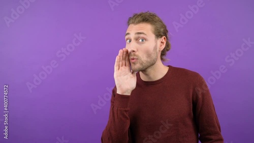 portrait of a young mysterious long-haired guy who shares a secret while holding his palm over his mouth 4K photo