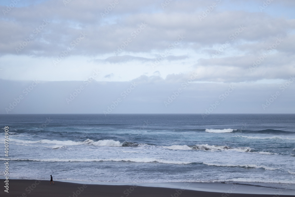 Men walking on the beach on a stormy day, winter at Azores, Ribeira Grande beach.