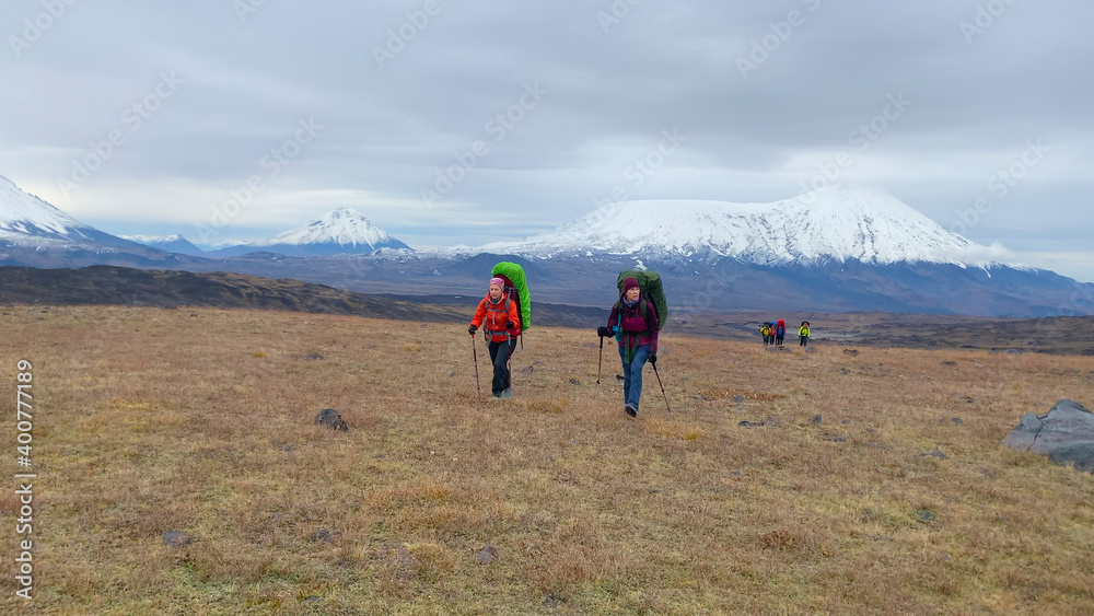 A group of tourists against the backdrop of the majestic beautiful volcanoes of Kamchatka.