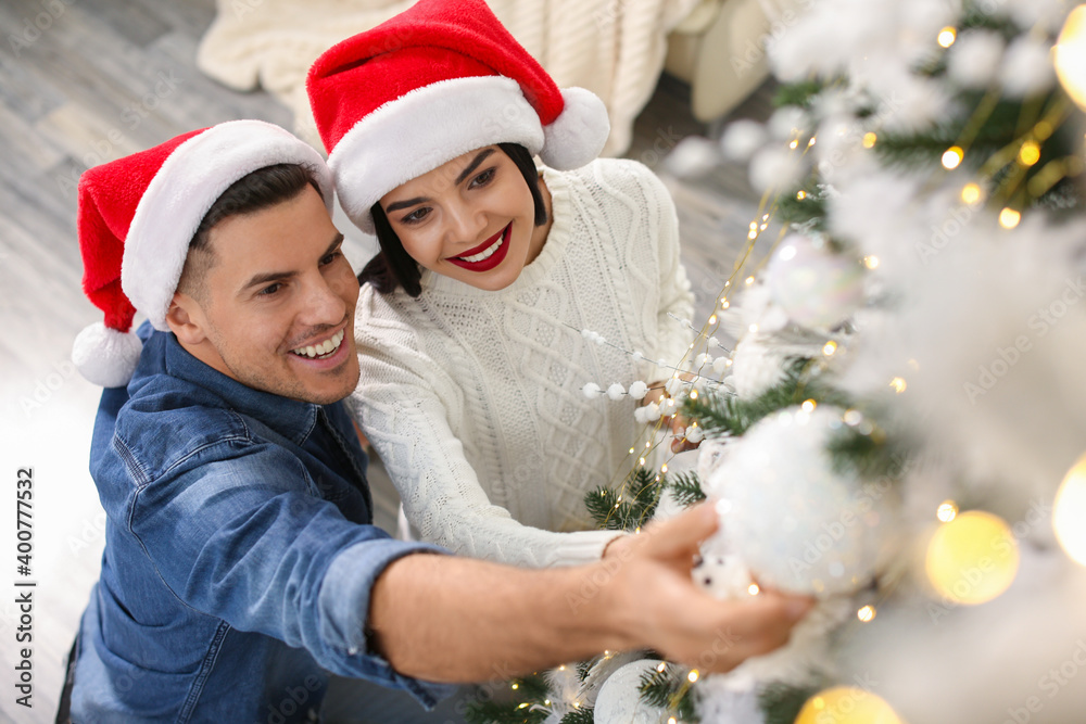 Happy couple decorating Christmas tree at home, above view Happy couple decorating Christmas tree at home, above view