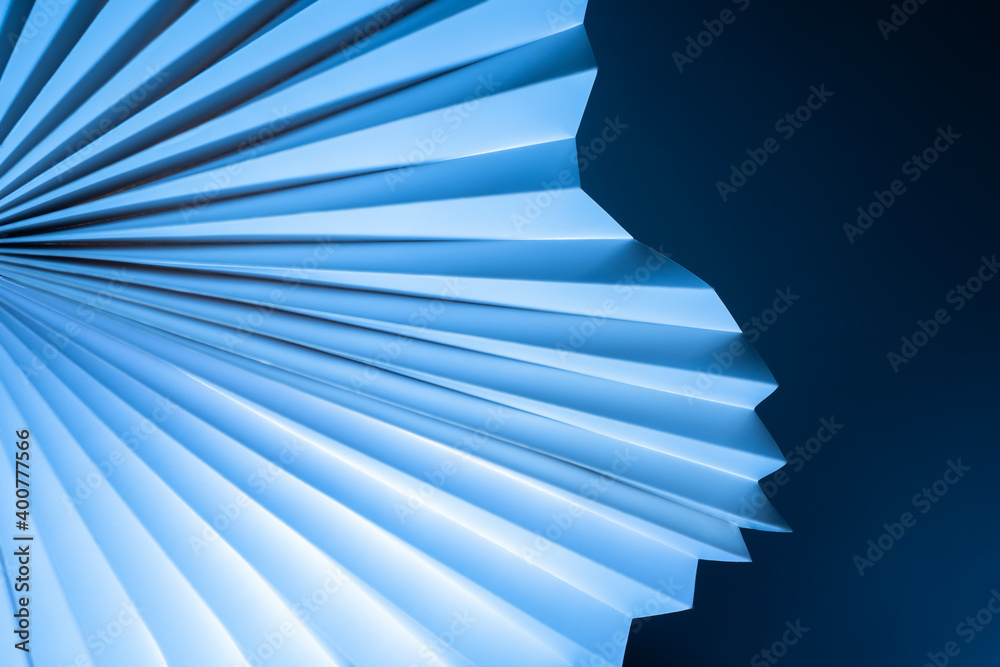 Blue-white three-dimensional background. Paper fan pattern on dark background. Geometric background with a three-dimensional cardboard object. Sometimes blurred abstract image. Blue-white three-dimensional background. Paper fan pattern on dark background. Geometric background with a three-dimensional cardboard object. Sometimes blurred abstract image.
