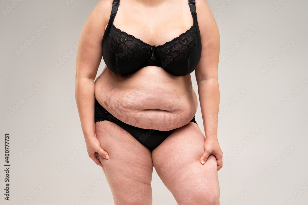 Fat woman in black lingerie, overweight female body on gray